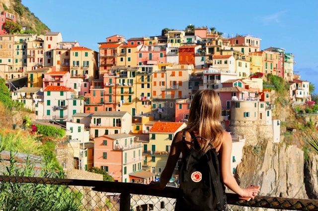 ragazza di spalle con uno zaino che osserva il panorama delle cinque terre in Italia